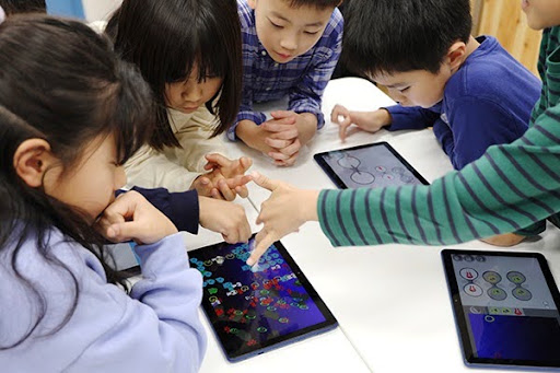 子どもたちがタブレットを使ってビスケットチャレンジの作品を見せ合っている様子